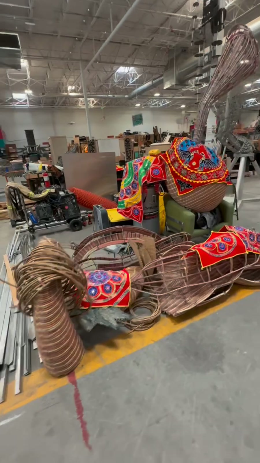 Woven cane sculpture sections draped in red Pipili appliqué textiles, staged on the floor of the Reno Generator build space.